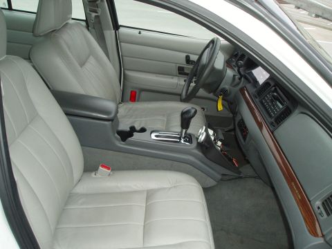 2003 Ford Crown Victoria - Interior view of a 2003 Ford Crown Victoria, highlighting the light gray leather seats, dashboard, and center console.