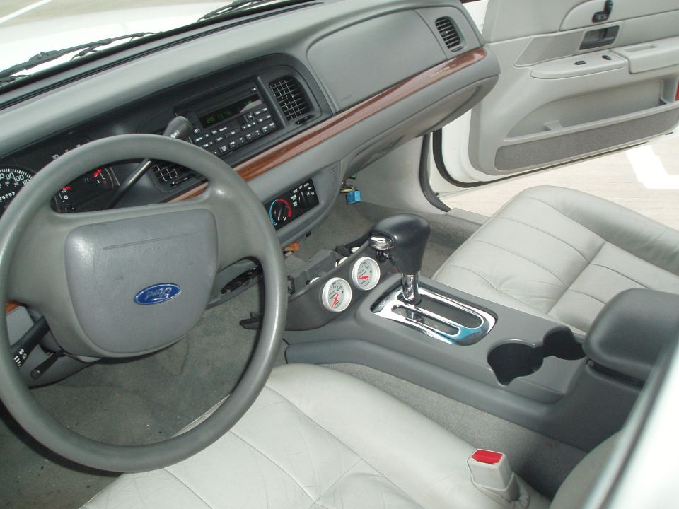 Gray Crown Victoria interior with wood trim, floor shifter and two aftermarket gauges