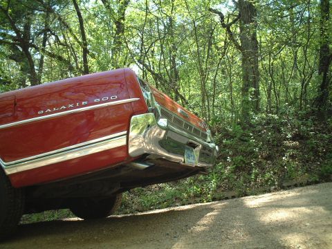 1967 Ford Galaxie - The rear quarter of a red 1967 Ford Galaxie 500 is visible, chrome accents and the 'Galaxie 500' badging.
