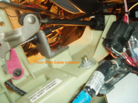 2003 Ford Crown Victoria - Close-up of a floor shift cable installation on a vehicle's transmission or steering column area, showing a metal shift lever, black cable…