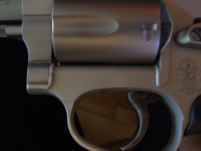 Close-up of a revolver cylinder and trigger guard. Smith & Wesson logo visible