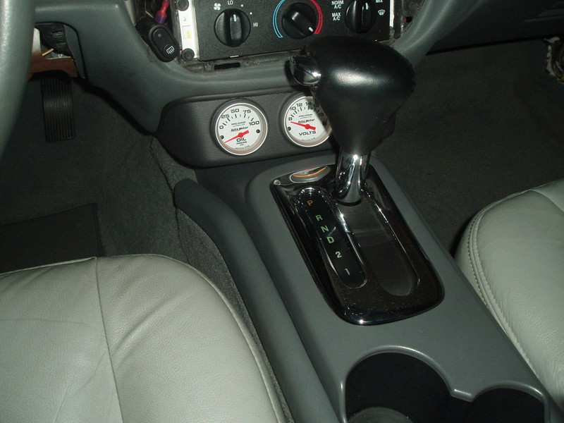 Car interior center console with automatic shifter and aftermarket oil and volt gauges