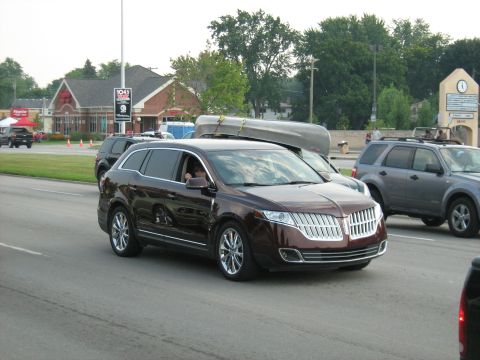 1988 Mercury Grand Marquis - A brown Lincoln MKT is seen from the front-right angle, carrying a canoe on its roof during a cruise event.