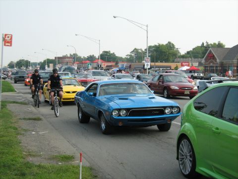 1988 Mercury Grand Marquis - A blue 1970 Dodge Challenger is seen in traffic alongside other vehicles and cyclists.