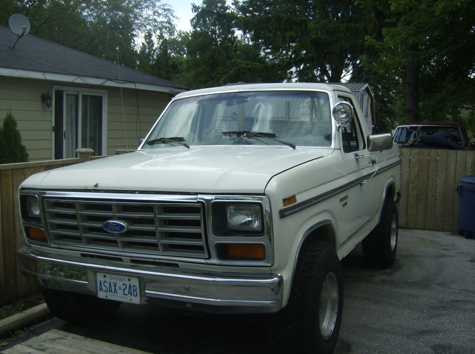 White Ford Bronco, front 3/4 view, parked in driveway. Chrome grille, chrome bumper, license plate ASAX-248