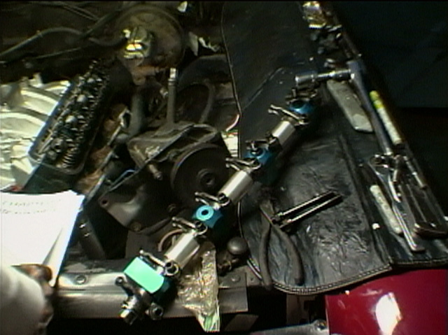 Adjustable roller rocker arms with blue and green anodized parts on an engine cylinder head