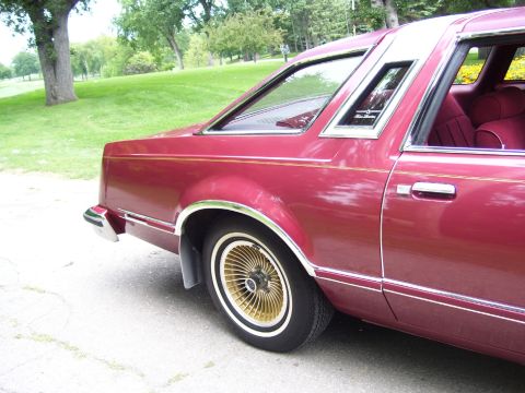1979 Ford Thunderbird - Rear side view of a maroon 1979 Ford Thunderbird with gold turbine wheels.