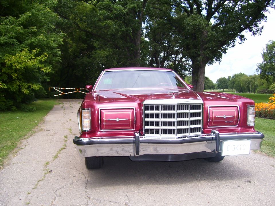 Front view of a red 1977 Ford Thunderbird parked on a gravel driveway