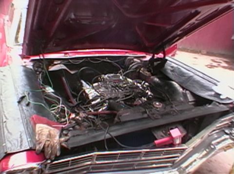 1967 Ford Galaxie - The engine bay of a red 1967 Ford Galaxie is visible with its hood open, showing the engine and wiring.