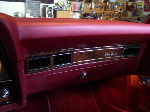 1979 Ford Thunderbird - The interior dashboard of a red car shows wood grain trim and air vents, with "Elite" text visible on the trim.