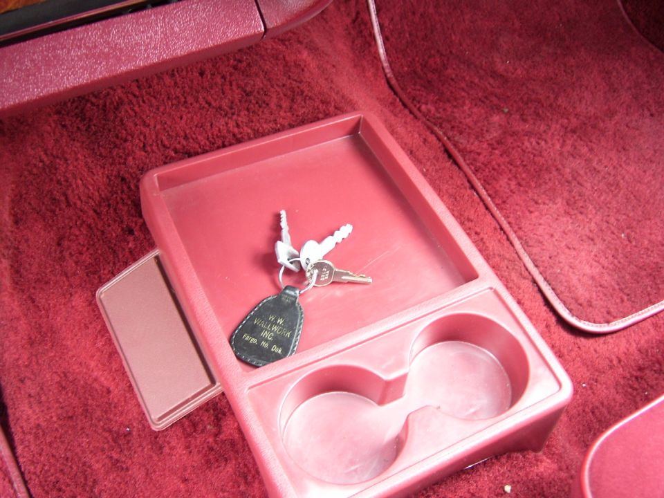 Interior console with keys and cup holders. Key fob reads 'H.W. Wallwork Inc. Fargo, ND Dak.'
