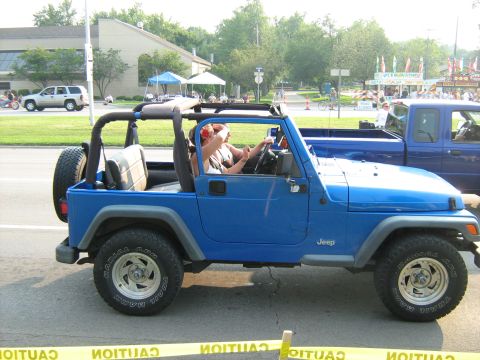 1988 Mercury Grand Marquis - A blue Jeep Wrangler is seen from the side, with a blue pickup truck behind it.