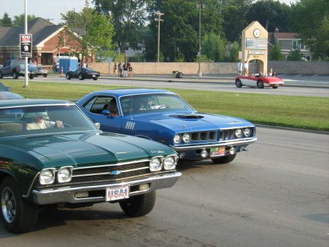 1988 Mercury Grand Marquis - A blue 1970 Plymouth Barracuda is parked next to a green Chevrolet during a car show.