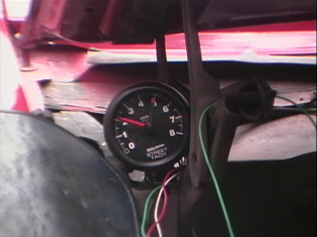 Auto Meter Street Tach mounted with loose colored wiring in an unfinished car interior