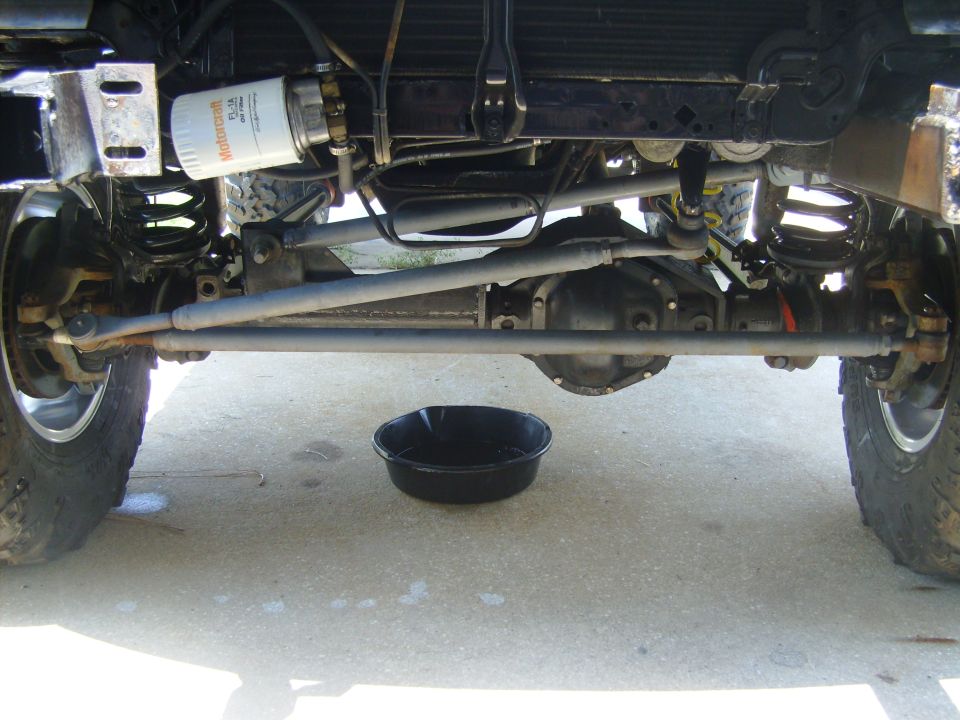Underside of a 4x4 truck front axle with oil drain pan