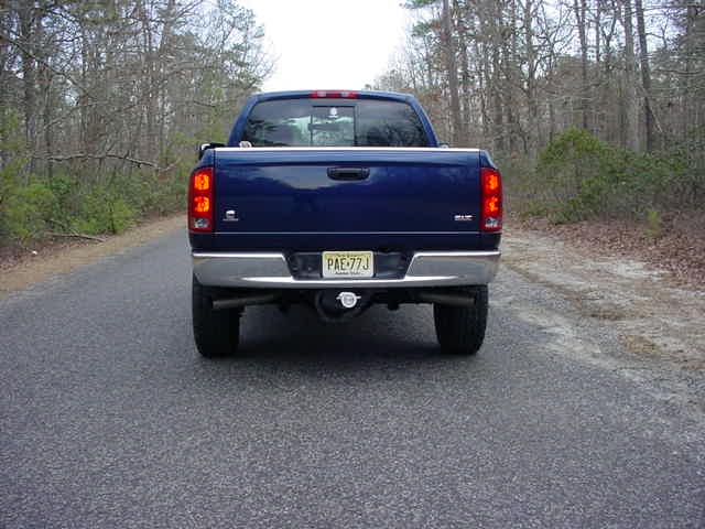 Rear view of dark blue Dodge Ram pickup with chrome bumper and NJ plate on a wooded road