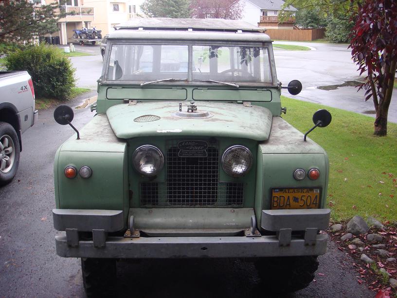 Green Land Rover Series IIA with a yellow Alaska license plate, parked outdoors