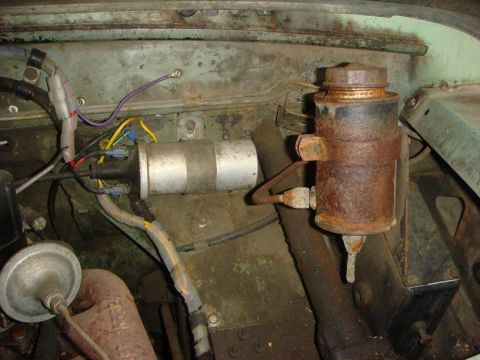 1967 Land Rover Land Rover - Close-up view of engine bay components including a rusty canister and ignition coil.