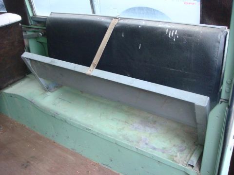 1967 Land Rover Land Rover - The interior of a vehicle shows a bench seat with a worn black cushion and a metal tray.
