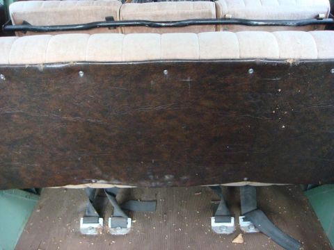 1967 Land Rover Land Rover - Interior view of a vehicle with beige seats and brown paneling, showing seatbelts on the floor.