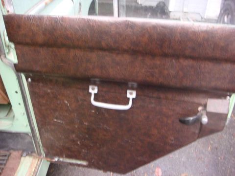 1967 Land Rover Land Rover - Close-up of a worn brown vinyl door panel with a white pull handle and a black door handle, showing interior details.