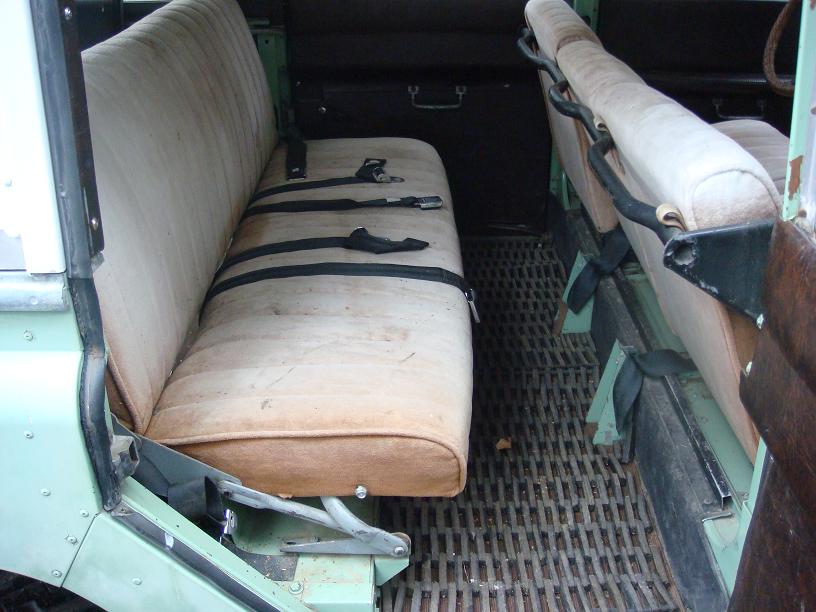 Interior view of a 1967 Land Rover Land Rover showing front and rear bench seats with seatbelts and a ribbed floor
