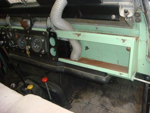 1967 Land Rover Land Rover - Dashboard view of a vehicle, gauges, vents, and gear shifters. The dashboard is painted green.