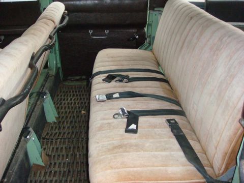 1967 Land Rover Land Rover - The interior of a vehicle features bench seats with seatbelts and a metal floor mat.