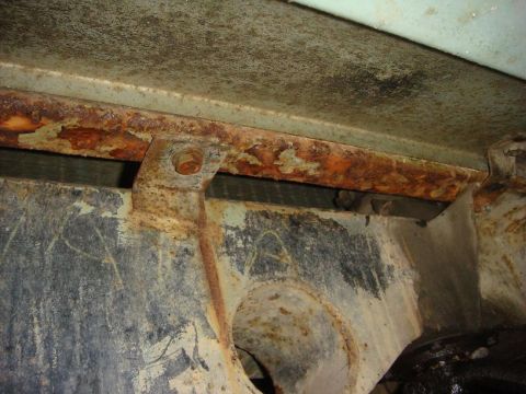1967 Land Rover Land Rover - Close-up view of a heavily rusted metal frame, showing bolts and brackets.