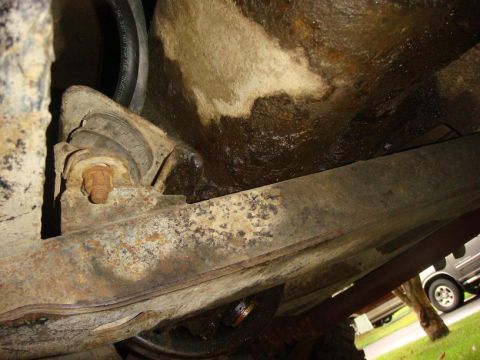 1967 Land Rover Land Rover - Undercarriage view showing a rusty bracket and hose, with a van visible in the distance.