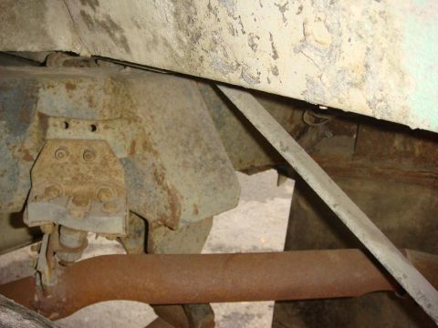 1967 Land Rover Land Rover - Close-up view of the heavily rusted undercarriage of a vehicle, showing structural components and an exhaust pipe.