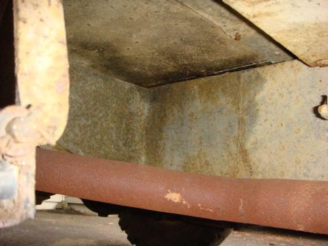 1967 Land Rover Land Rover - Close-up view of a heavily rusted vehicle undercarriage, showing a large exhaust pipe and suspension parts.