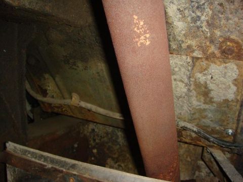 1967 Land Rover Land Rover - Close-up view of a rusty exhaust pipe and the corroded undercarriage of a vehicle.
