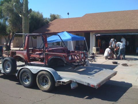 Suzuki Samurai - A dark red Suzuki Samurai body/tub stripped of doors, top, and drivetrain sits on a dual-axle flatbed utility trailer in a residential driv…