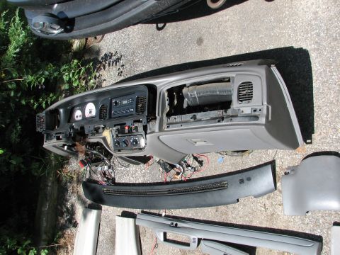 1999 Ford Crown Victoria - The dashboard and surrounding trim pieces are laid out on the ground, showing exposed wiring and internal components.