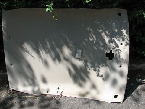 1999 Ford Crown Victoria - A detached car headliner is laid out on the ground, with shadows of leaves falling on it.