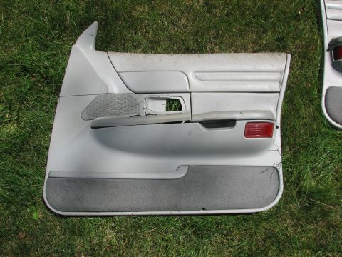 1999 Ford Crown Victoria - Gray interior door panel with speaker grille and red reflector, likely from a Ford Crown Victoria.