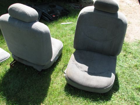 1999 Ford Crown Victoria - Two front car seats are displayed outdoors on a grassy lawn, with a car door visible in the background.