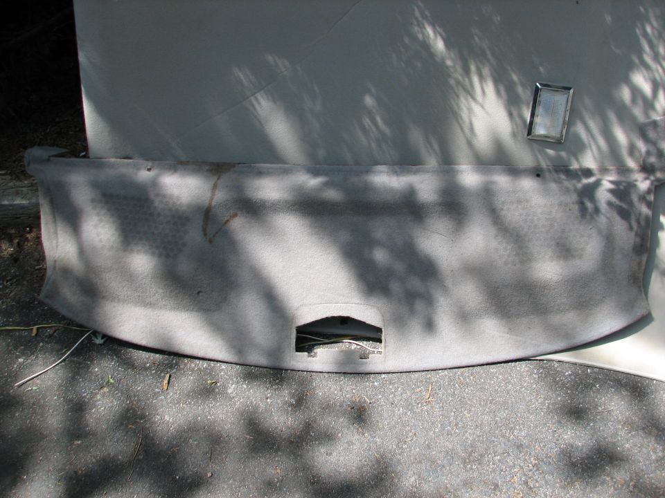 Car headliner with a cutout for a light and a small rectangular mirror attached