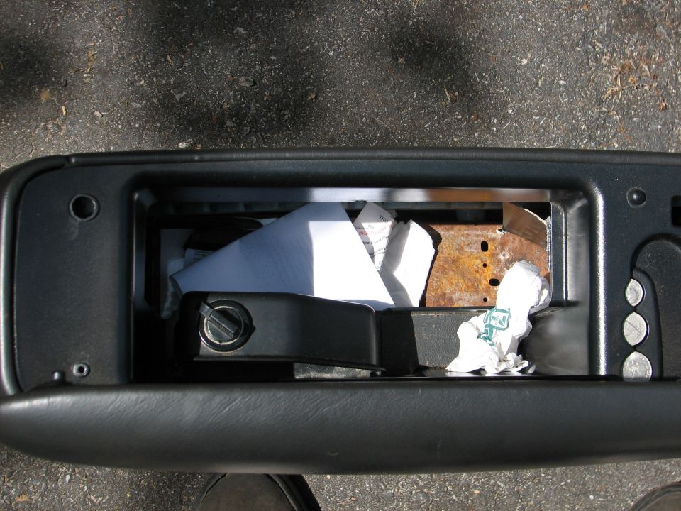 Open glove box interior with papers and rusty bracket