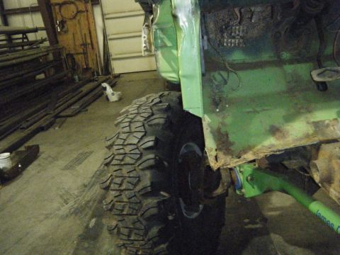 1978 Ford Bronco - A close-up view of a green off-road vehicle's side, highlighting its large tire and areas of rust.