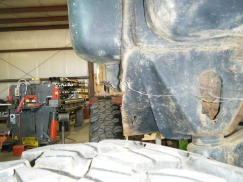 1978 Ford Bronco - A close-up view of a vehicle's frame and tire, with industrial equipment visible in the background.