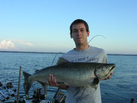 1990 Ford Bronco - Man proudly displays a large salmon catch while on a boat with fishing gear visible.