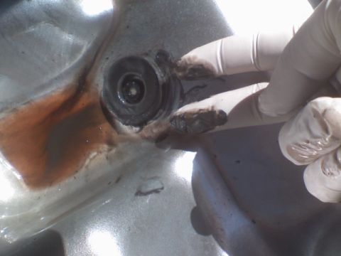 1993 Ford Bronco - Close-up of a transmission drain plug showing dark fluid and debris, with gloved hands present.