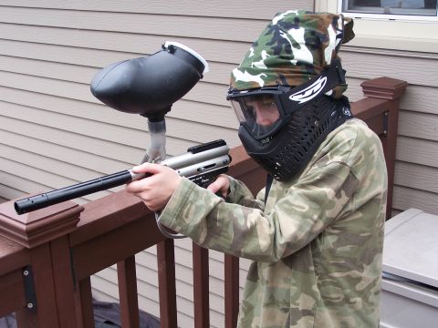1986 Ford Bronco - A person wearing a camouflage bandana, mask, and shirt holds a paintball gun.