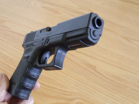 2002 Jeep TJ - A black semi-automatic pistol is held in hand against a wooden background.