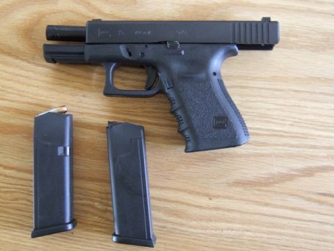2002 Jeep TJ - A black semi-automatic pistol and two magazines are displayed on a wooden table.