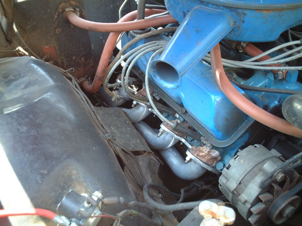 Engine bay with blue valve cover, orange plug wires, gray manifold and alternator