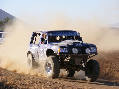 1986 Ford Bronco - A modified Ford Bronco competes in a desert race, kicking up a large cloud of dust.