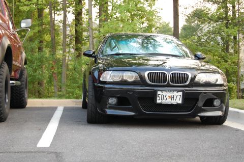 2002 BMW M3 - A black BMW M3 is parked in a parking lot, with a brown SUV to its left.